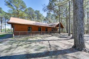 a log cabin in the woods with a tree at Lavish Cabin Hot Tub and Deck, Near Broken Bow Lake in Broken Bow