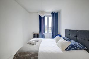 sypialnia z dużym łóżkiem z niebieskimi zasłonami w obiekcie Le bien-être au cœur de la ville confort & vue w mieście Périgueux