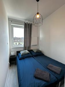 - une chambre avec un lit bleu et une fenêtre dans l'établissement Apartament Szczecin, à Szczecin