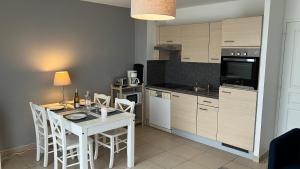 a kitchen with a white table and chairs and a kitchen with a stove at F50 Ferme de Deauville 1 CH rez-de-jardin avec escalier in Saint-Arnoult