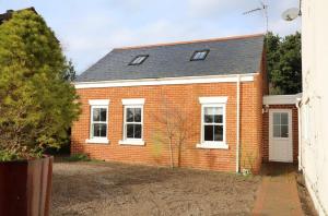 a red brick house with a white door at The Cosy West Wing, dog friendly in Martham