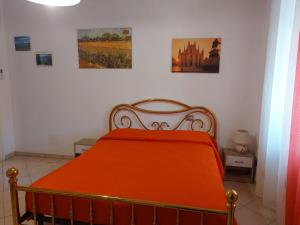 an orange bed in a room with pictures on the wall at Grazioso Monolocale Bellagio in Bellagio