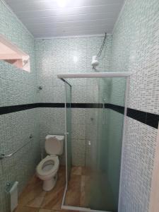 a bathroom with a toilet and a glass shower stall at Ótima casa de praia, muito bem localizada. in São Sebastião