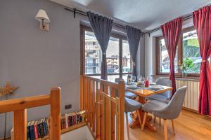 a dining room with a table and chairs and windows at Casa Julie - CIR COURMAYEUR 0157 - in Courmayeur