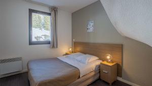 a bedroom with a bed and a window and two lamps at Madame Vacances Les Terrasses De Véret in Flaine