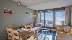 een eetkamer en een woonkamer met een tafel en een bank bij Madame Vacances Les Terrasses De Véret in Flaine