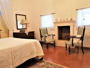 1 dormitorio con 1 cama, 2 sillas y chimenea en Autentica Masseria Pugliese, en Putignano