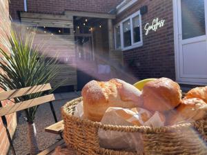 a basket full of bread sitting on a bench at Sea Glass Cottage - Luxury hotel style 3 bed with hot tub in Seaham