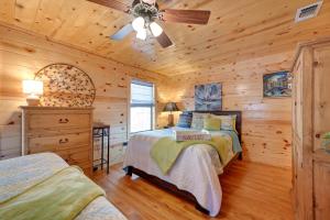 Dormitorio en cabaña de madera con 2 camas y ventilador de techo en Broken Bow Cabin with Hot Tub and Fire Pit, en Broken Bow