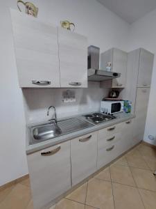 eine Küche mit weißen Schränken, einer Spüle und einer Mikrowelle in der Unterkunft Studio Casta in Bellagio