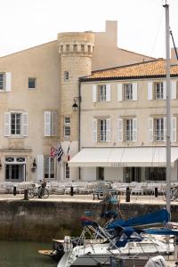 un barco atracado en un puerto deportivo frente a un edificio en Hôtel de Toiras en Saint-Martin-de-Ré