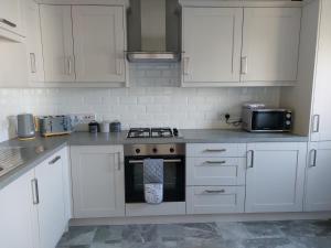 een keuken met witte kasten en een fornuis met oven bij Bellman 12, Newly Refurbished 2023, Lake View, Pet Friendly in Bowness-on-Windermere