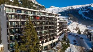 a building with a tree in front of a mountain at Madame Vacances Les Terrasses De Véret in Flaine