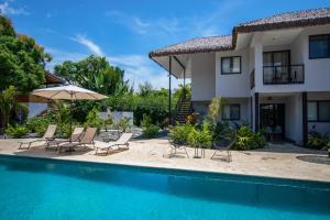 a house with a swimming pool with chairs and an umbrella at Yuli Hotel in Uvita