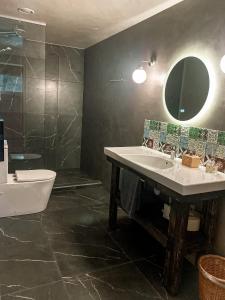 a bathroom with a sink and a tub and a mirror at Saarjärve Puhkemaja 16-le 4 magamistuba in Tromsi