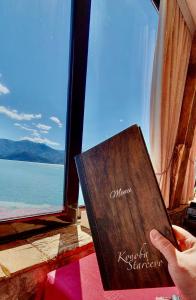 a person holding a book in front of a window at Apartmani Konoba Starčevo in Virpazar