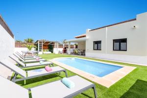 a villa with a swimming pool and lawn at Villa Caleta Del Sol by Villa Plus in Caleta De Fuste