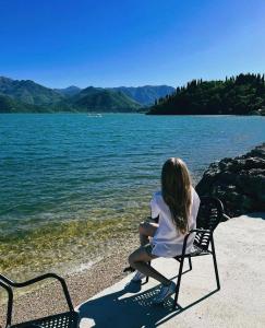 a woman sitting on a bench next to a lake at Apartmani Konoba Starčevo in Virpazar