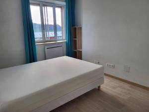 1 dormitorio con cama blanca y ventana en appartement 40 m² proche rempart, en Langres