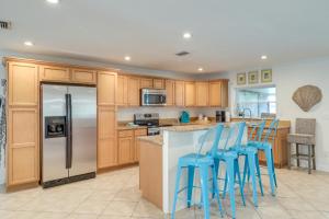 a kitchen with wooden cabinets and blue bar stools at Beach Retreat in Jacksonville Pet and Family-Friendly in Jacksonville Beach