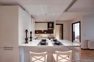 eine weiße Küche mit einem Herd und Stühlen in der Unterkunft Luxury Residence in Şişli (Pool/Garage/Gym) in Istanbul