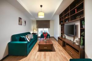 a living room with a green couch and a television at Luxury Residence in Şişli (Pool/Garage/Gym) in Istanbul