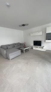 a white living room with a couch and a tv at 4 ZKB Neubauwohnung mit Stil in Bielefeld