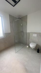a bathroom with a glass shower and a toilet at 4 ZKB Neubauwohnung mit Stil in Bielefeld