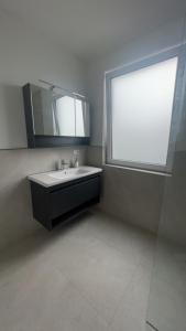 a bathroom with a sink and a large window at 4 ZKB Neubauwohnung mit Stil in Bielefeld