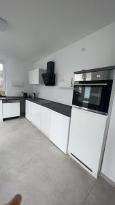 uma cozinha com armários brancos e um forno com placa de fogão em 4 ZKB Neubauwohnung mit Stil em Bielefeld