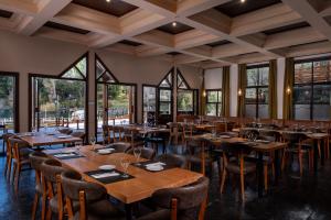a restaurant with wooden tables and chairs and large windows at Manzano Resort in Villa La Angostura