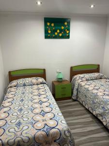 a bedroom with two beds and a painting on the wall at Apartamentos Joaquina in Tagle