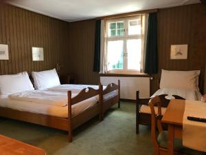 a bedroom with two beds and a table and a window at Gasthaus zum Goldenen Kreuz in Rafz