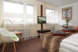 a hotel room with a bed and a tv and windows at Hotel Vetter in Nürtingen