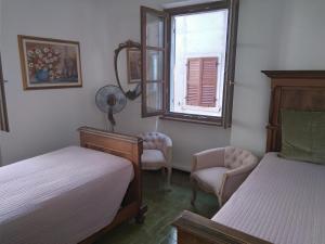 a bedroom with two beds and a window and a chair at Originari del Garda in Garda