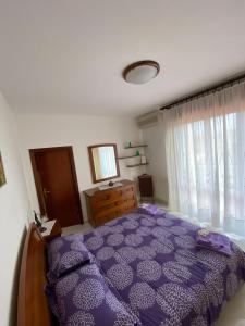 ein Schlafzimmer mit einem lila Bett, einer Kommode und einem Fenster in der Unterkunft Casa Anna in Portoferraio