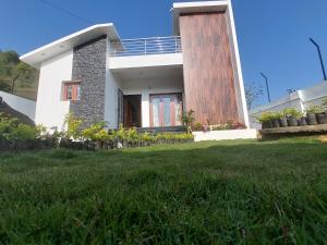 a house with a green lawn in front of it at Kodai Diva Inn - Home Stay in Kodaikānāl