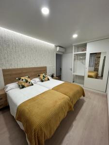 ein Schlafzimmer mit einem großen Bett und einer gelben Decke in der Unterkunft A CASIÑA DE ISABEL in Arzúa