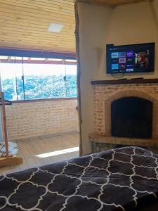 1 dormitorio con chimenea y TV de pantalla plana en Recanto das Glicínias en Monte Verde