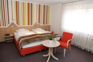 a bedroom with a bed and a table and a chair at Hotel Vetter in Nürtingen