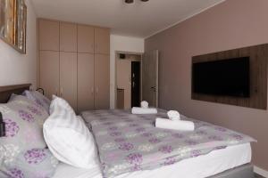 a bedroom with a large bed with pillows and a tv at Villa Bauhaus Wellness Apartman in Siófok +23 photos