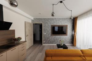 a living room with a couch and a tv at Villa Bauhaus Wellness Apartman in Siófok