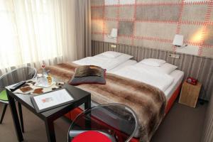 a hotel room with a bed, desk, and nightstand at Hotel Vetter in Nürtingen