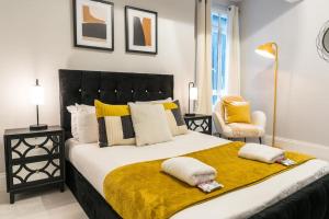 una camera da letto con un grande letto con cuscini gialli e bianchi di Exceptional 5 stars flat in lovely location a Londra