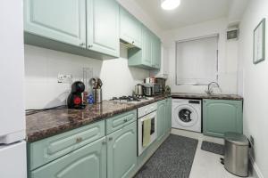 cocina con armarios verdes, lavadora y secadora en Exceptional 5 stars flat in lovely location en Londres