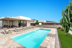 einen Pool mit Stühlen und ein Haus mit Kaktus in der Unterkunft Villa Salvia by Villa Plus in Playa Blanca