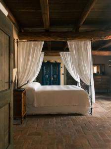 B&B Cascina Mattarelle في مونزامبانو: غرفة نوم بسرير مع شراشف بيضاء وستائر