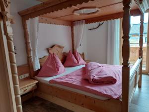 1 dormitorio con cama de madera con dosel y almohadas rosas en Ferienwohnung Almsuite Fritz en Wald im Pinzgau