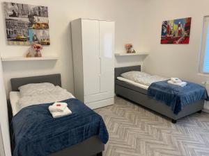 2 letti in una camera da letto con lenzuola bianche e blu di Apartment am Grünen Ring a Herne