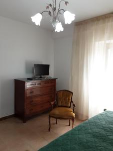 um quarto com uma cómoda, uma televisão e uma cadeira em La Cascina di Fox em Terni